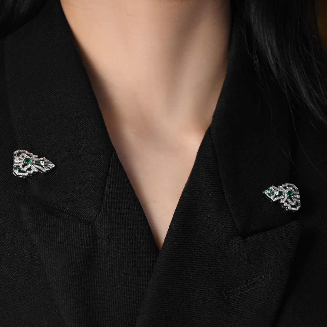 Introducing our versatile Art Deco-inspired brooch adorned with clear geometric lines, fully encrusted in shimmering white melee diamonds and accented by stunning emeralds. This unique piece not only exudes elegance with its intricate design but can also transform into two individual lapel pins, offering versatility for a variety of styling options.