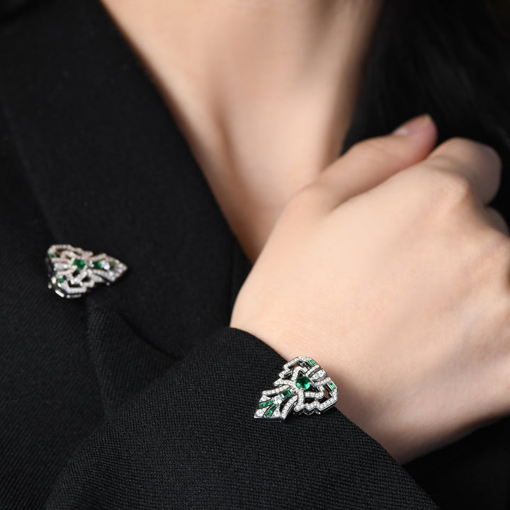 Introducing our versatile Art Deco-inspired brooch adorned with clear geometric lines, fully encrusted in shimmering white melee diamonds and accented by stunning emeralds. This unique piece not only exudes elegance with its intricate design but can also transform into two individual lapel pins, offering versatility for a variety of styling options.