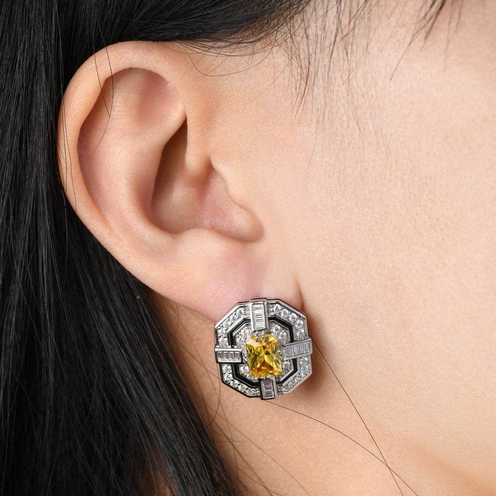 Immerse yourself in the timeless allure of our Art Deco-inspired earrings, where geometric elegance meets opulence. The intricate design, fully adorned with white melee diamonds, frames a central yellow radiant-cut diamond, while an elegant black line, crafted using the Cold Enamel technique, adds a touch of depth, making these earrings a sophisticated and eye-catching accessory.