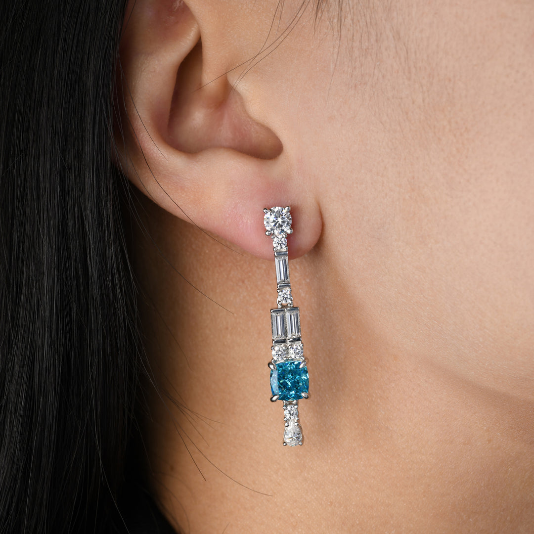 Immerse yourself in the allure of our earrings showcasing a captivating cushion-cut blue simulated diamond as the centerpiece. Enhanced by complementary white diamonds in varying shapes, this pair elegantly captures a harmonious blend of sophistication and brilliance, making it a standout addition to any ensemble.