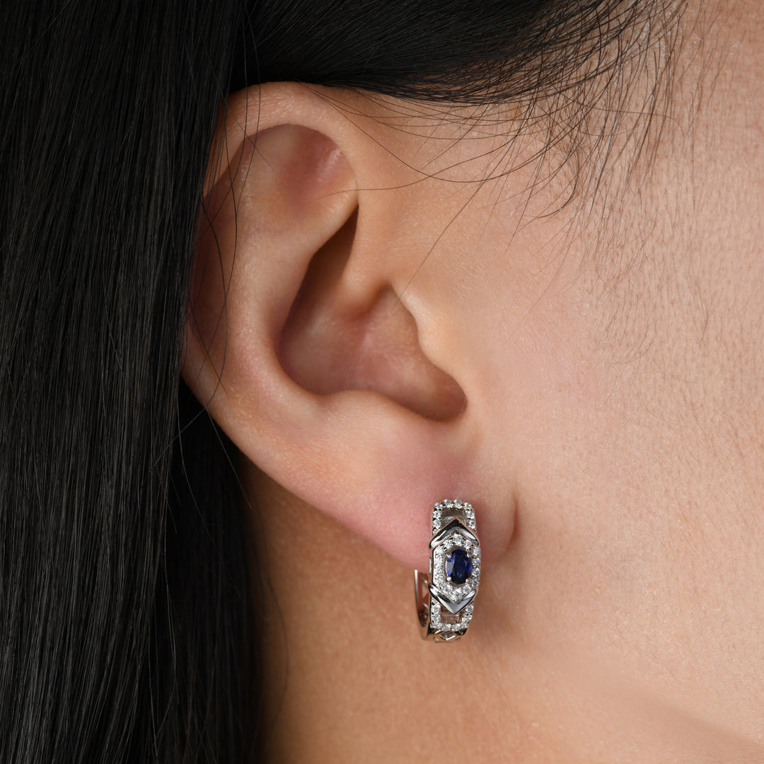 This pair of earrings featuring an oval sapphire delicately nestled on a platinum base adorned with white simulated diamonds. The simple and classic design of these earrings adds a touch of sophistication, making them the perfect accessory for any occasion