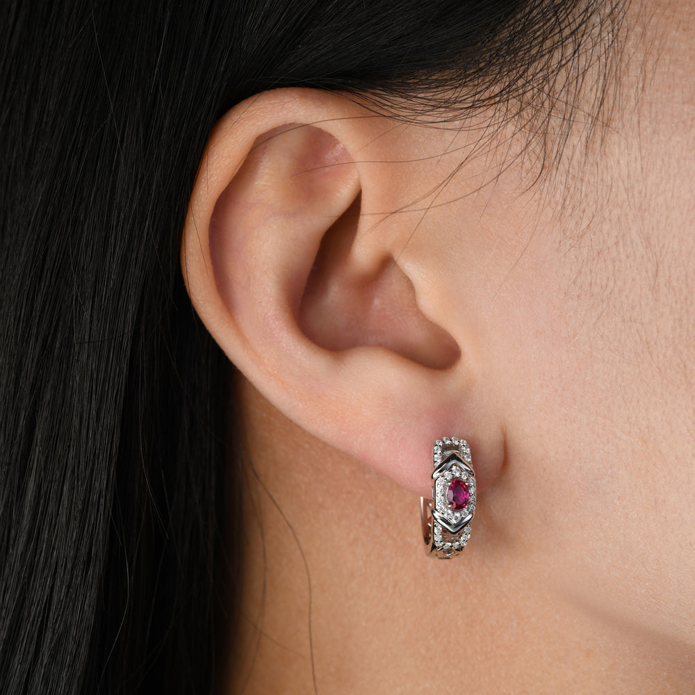 This pair of earrings featuring an oval ruby delicately nestled on a platinum base adorned with white simulated diamonds. The simple and classic design of these earrings adds a touch of sophistication, making them the perfect accessory for any occasion