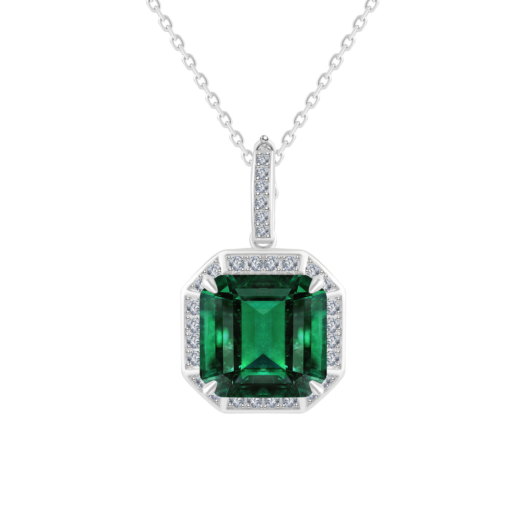 Experience timeless beauty with our exquisite pendant, where a resplendent emerald takes center stage, encircled by delicate round simulated diamonds. The Asscher-cut-shape metal base adds a touch of sophistication, while a dainty ring, inlaid with diamonds, graces the top, creating a perfect blend of luxury and elegance in one captivating piece.